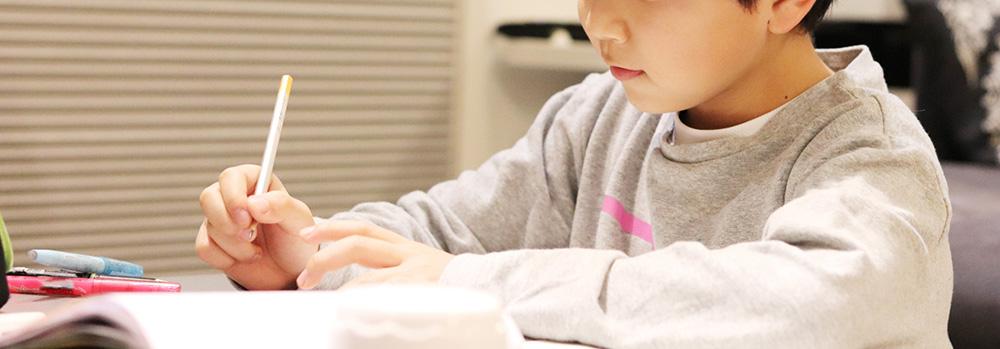机に向かい問題を解く少年